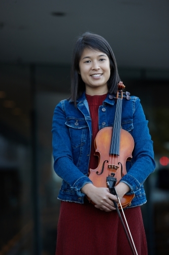 Young Asian female violin player practising outdoors - Australian Stock Image