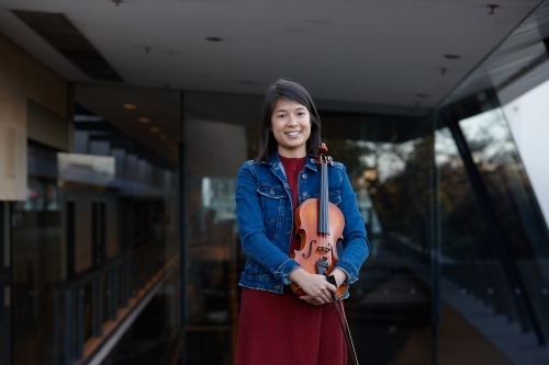 Young Asian female violin player practising outdoors - Australian Stock Image