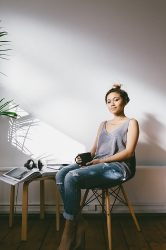 Young asian girl looking contently at home in her apartment - Australian Stock Image