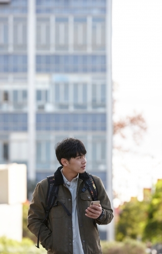 Young Asian university student using mobile phone on-campus - Australian Stock Image