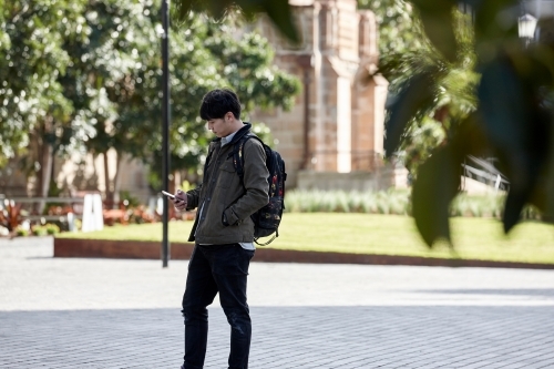 Young Asian university student using mobile phone on-campus - Australian Stock Image