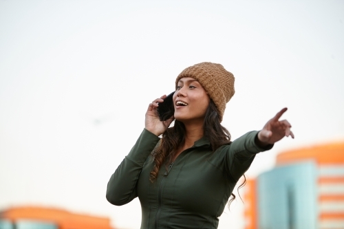 Young Asian woman hailing taxi whilst on mobile phone in city - Australian Stock Image