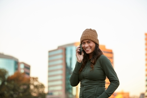 Young Asian woman having fun talking on mobile phone in city - Australian Stock Image
