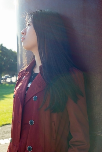 Young Asian woman standing by metal sculpture - Australian Stock Image