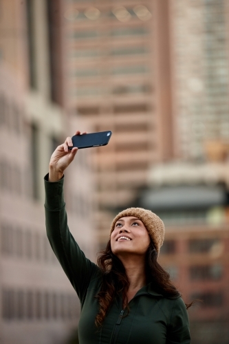 Young Asian woman taking a selfie with mobile phone in city - Australian Stock Image