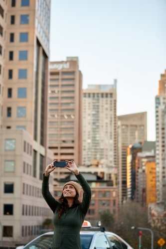 Young Asian woman taking a selfie with mobile phone in city