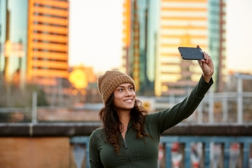 Young Asian woman taking a selfie with mobile phone in city - Australian Stock Image