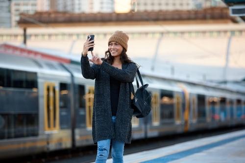Young Asian woman taking selfie at train station