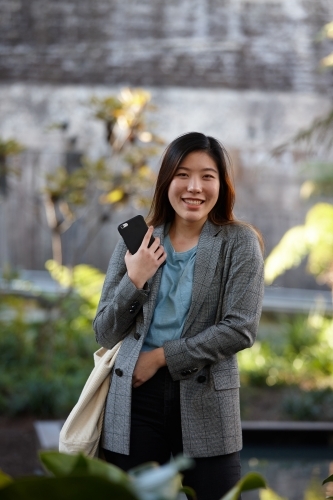 Young Asian woman with shopping bag outdoors at enclave - Australian Stock Image