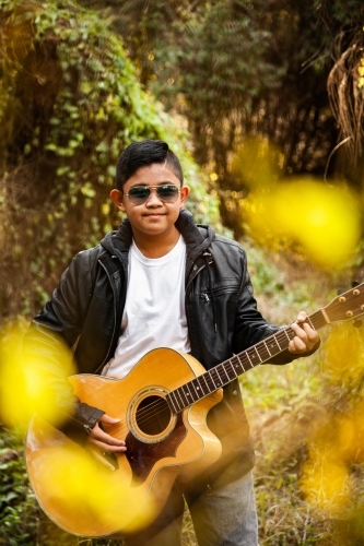 Young aussie boy wearing sunnies and playing guitar - Australian Stock Image