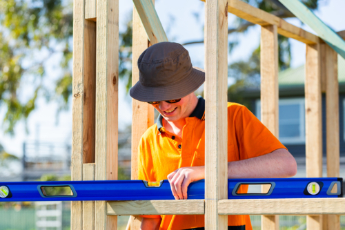 Young aussie teen trade apprentice using level on frame at worksite - Australian Stock Image