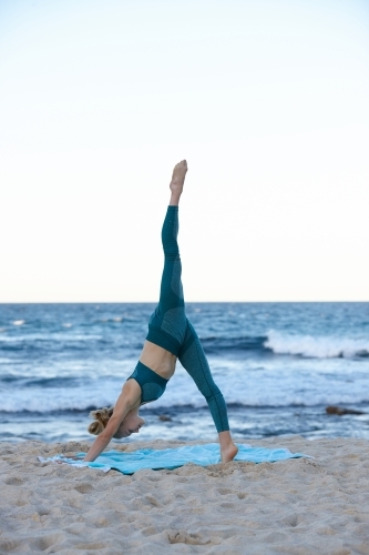 Young blonde-haired woman at beach doing yoga - Australian Stock Image