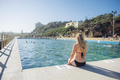 Young blonde Woman sitting on the side of an ocean pool