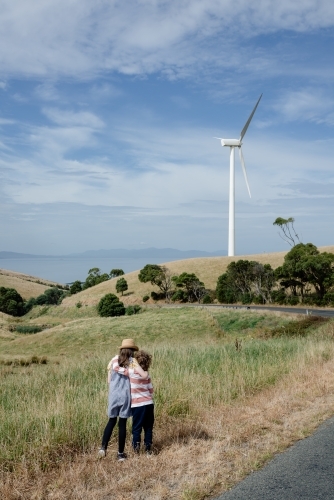 Young boy and girl together in rural Gippsland near Toora, with a wind turbine in the distance - Australian Stock Image