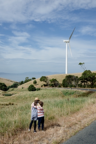 Young boy and girl together in rural Gippsland near Toora, with a wind turbine in the distance