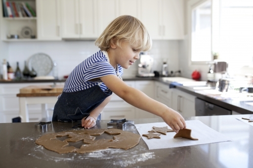Young boy baking gingerbread biscuits in kitchen at home - Australian Stock Image
