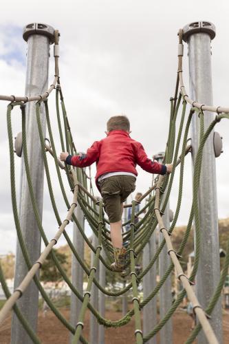 Young boy climbing playground equipment at park - Australian Stock Image