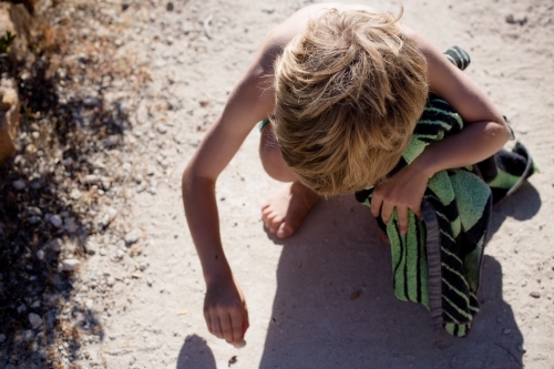 Young boy drawing in the sand - Australian Stock Image