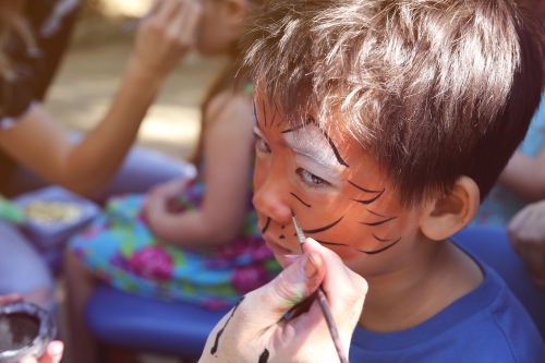 Young boy getting face painted as a tiger - Australian Stock Image