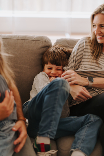 Young boy giggling while snuggling into mums side. - Australian Stock Image