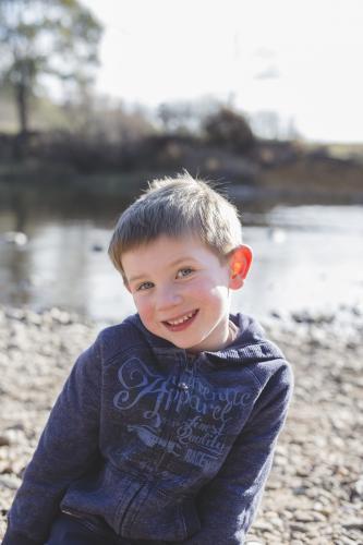 Young boy grinning beside a river