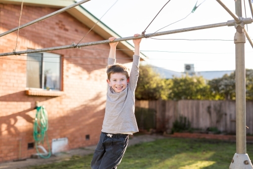 Young boy hanging from washing line