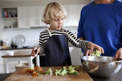 Young boy helping prepare vegetables for dinner - Australian Stock Image