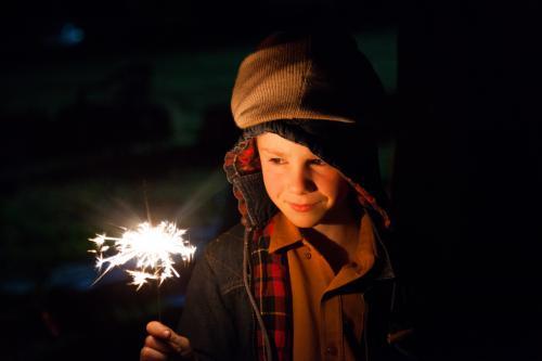 Young boy holding a burning sparkler on a bonfire night