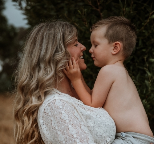 Young boy holding his mother's face in his hands - Australian Stock Image