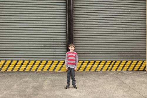 Young boy in front of large roller door