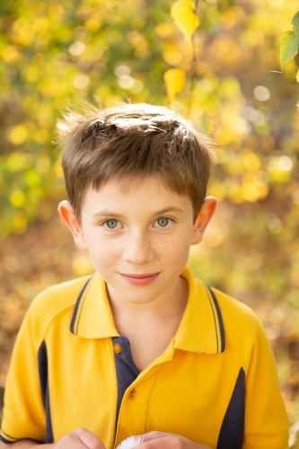 Young boy in yellow school uniform smiling - Australian Stock Image