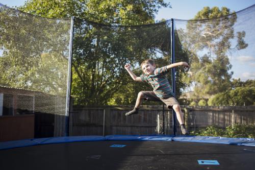 Young boy jumping on trampoline - Australian Stock Image