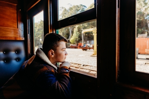 Young boy looking out open window on train
