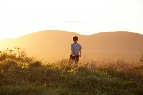Young boy looking out to mountains at sunset