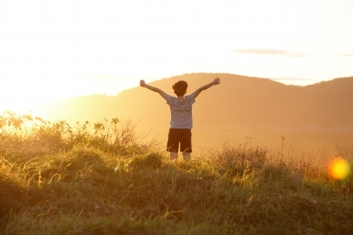 Young boy looking out to mountains at sunset - Australian Stock Image