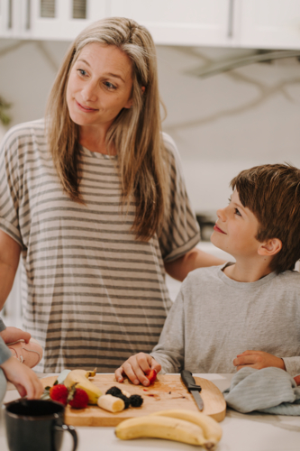 Young boy looking up to mum while holding a fruit. - Australian Stock Image