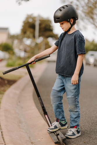 Young boy on his scooter on the street. - Australian Stock Image
