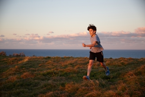 Young boy playing at headland on sunset