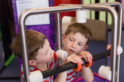 Young boy playing game looking into mirror at museum - Australian Stock Image