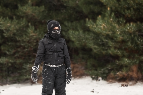 Young boy playing in snowy winter wonderland wearing snow suit - Australian Stock Image