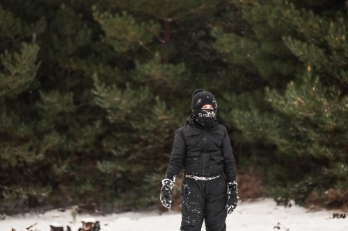 Young boy playing in snowy winter wonderland wearing snow suit - Australian Stock Image