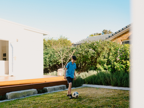 Young boy playing soccer in their garden. - Australian Stock Image