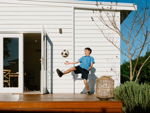 Young boy playing soccer on their garden deck. - Australian Stock Image