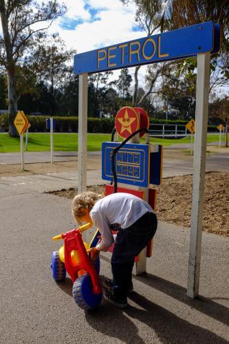 Young boy playing with toy bike pretending to fill with petrol - Australian Stock Image