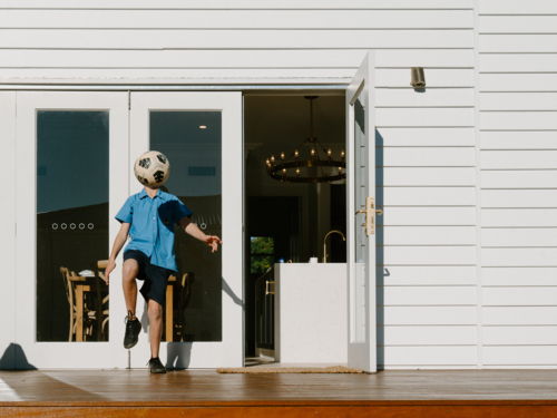 Young boy practicing soccer on their garden deck. - Australian Stock Image