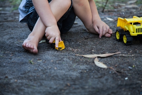 Young boy pushing toy digger in dirt - Australian Stock Image