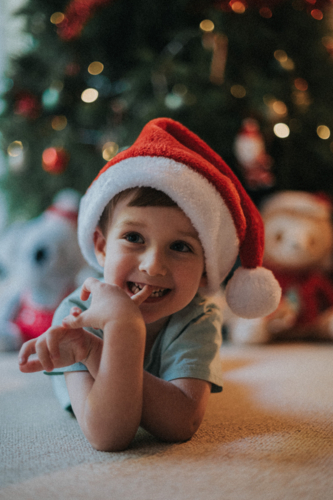 young boy radiates happiness in his Christmas hat - Australian Stock Image