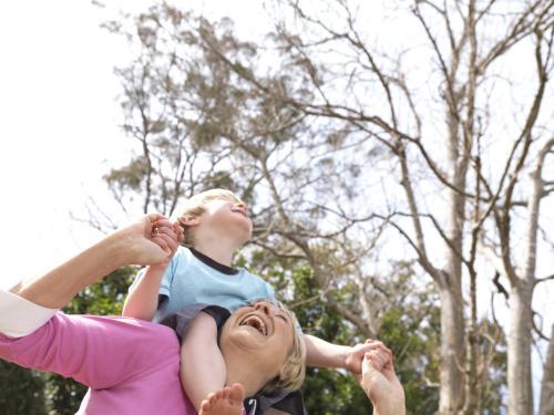 Young boy riding on shoulders of older woman - Australian Stock Image