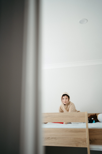 Young boy sitting on top of the bunk bed. - Australian Stock Image