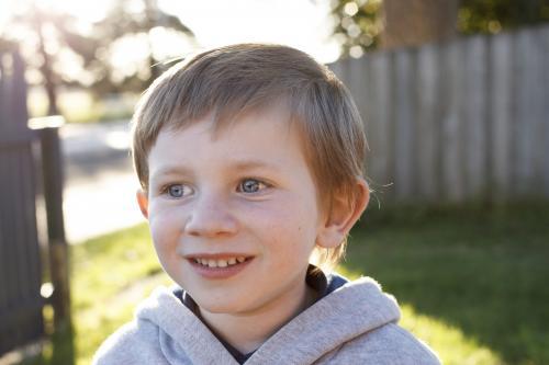 Young boy smiling in afternoon sun - Australian Stock Image
